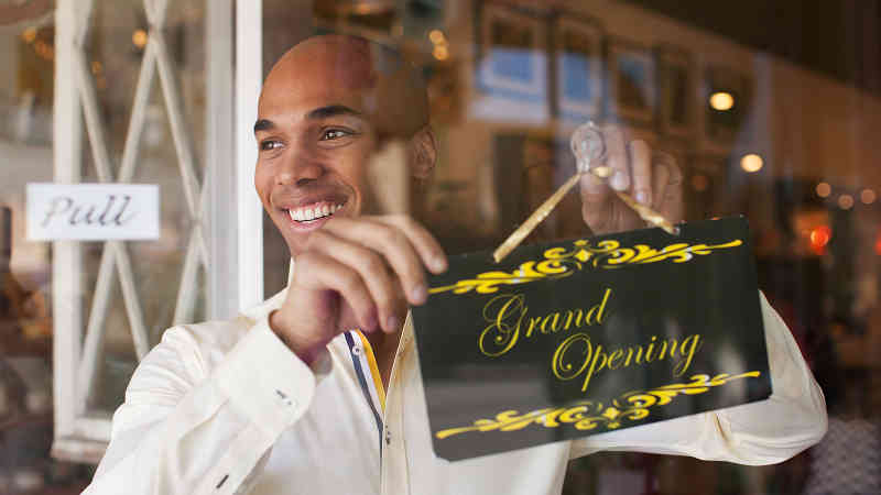 Businessman hanging Grand Opening sign in front window.