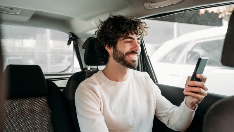 Man using phone in car and smiling