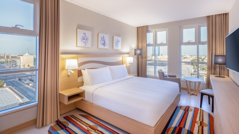 Bright hotel room with king-size bed, large windows, and city view in Residence Inn by Marriott.