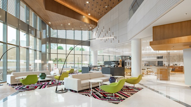 Radisson hotel lobby with natural light, contemporary furniture, and vibrant green chairs.